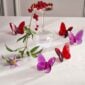 Baccarat Lucky Butterflies crystal sculptures in red and pink displayed with fresh flowers and an inverted crystal wine glass on a tabletop | Kneen & Co
