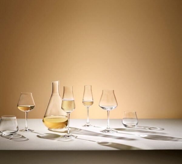 BACCARAT-2611149-2811925-2809869-2610986-Lifestyle-1200w-100KB Lifestyle image of the Château Baccarat Stemware collection featuring handcrafted Baccarat crystal wine glasses, champagne flute, tumbler, and decanter arranged on a softly lit table | Kneen & Co