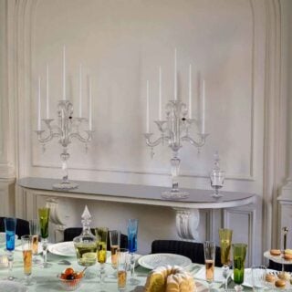Elegant dining table featuring Baccarat Mille Nuits crystal votives glowing among colorful crystal stemware, clear crystal decanters, and white dinnerware, with matching Baccarat crystal candelabras displayed in the background | Kneen & Co