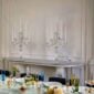 Elegant dining table featuring Baccarat Mille Nuits crystal votives glowing among colorful crystal stemware, clear crystal decanters, and white dinnerware, with matching Baccarat crystal candelabras displayed in the background | Kneen & Co