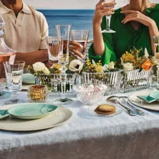 BACCARAT-2812544-2810597-1200w-100KB Baccarat Mille Nuits Flutissimo crystal Champagne flutes displayed on an outdoor dining table overlooking the water, paired with crystal stemware, floral arrangements, and elegant table settings | Kneen & Co