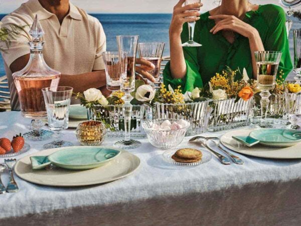 BACCARAT-2812544-2810597-1200w-100KB Baccarat Mille Nuits Flutissimo crystal Champagne flutes displayed on an outdoor dining table overlooking the water, paired with crystal stemware, floral arrangements, and elegant table settings | Kneen & Co