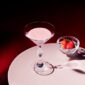 Baccarat Swing crystal bowl filled with fresh strawberries beside a Baccarat crystal cocktail glass on a white tabletop, showcasing the collection's faceted design and brilliant light reflections | Kneen & Co