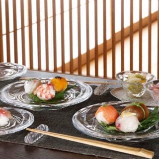 BACCARAT-2814080-Lifestyle-1200w-100KB Baccarat Swing crystal dinnerware and chopstick holders displayed with sushi, crystal bowls, and glassware, showcasing the collection's faceted design and contemporary table setting | Kneen & Co