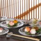 Baccarat Swing crystal dinnerware and chopstick holders displayed with sushi, crystal bowls, and glassware, showcasing the collection's faceted design and contemporary table setting | Kneen & Co