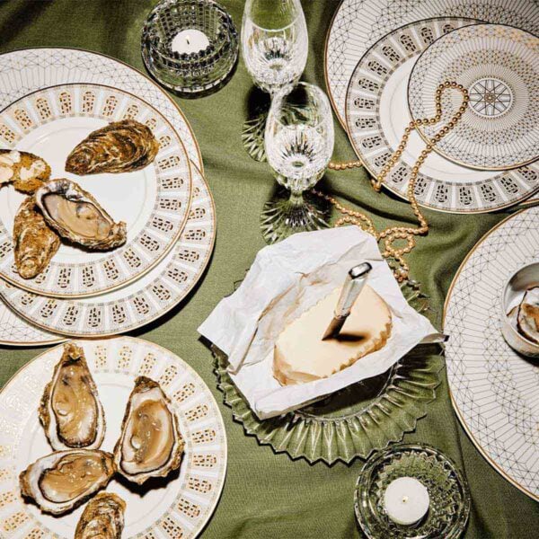 Baccarat Eye crystal votives displayed on an elegantly set dining table with Arcadia dinnerware, crystal stemware, fresh oysters, and caviar, adding a warm glow to the tablescape | Kneen & Co