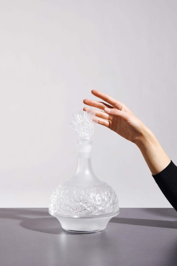 Minimalist studio setting with Lalique Versailles Decanter in clear and satin-finished crystal defined by an elegant sculptural silhouette and an intricately detailed floral stopper | Kneen & Co