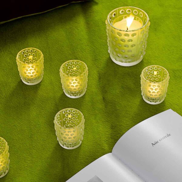 LALIQUE-1095600-MOSSI-VOTIVE-CLEAR-3-1200w-100KB Cozy interior setting with glowing Lalique Mossi Votives in clear crystal, featuring the iconic repeating cabochon pattern | Kneen & Co