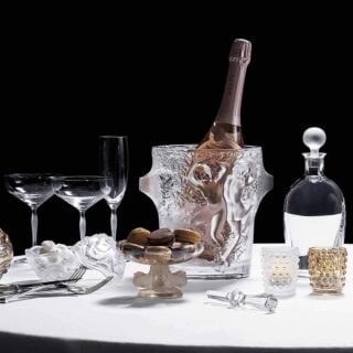 Elegant table setting featuring the Lalique Mossi Votive in clear crystal with repeating cabochons creating a kaleidoscopic light effect, alongside champagne and crystal barware | Kneen & Co
