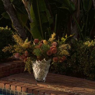Lush outdoor poolside setting featuring the Lalique Champs-Élysées Vase in clear and frosted crystal | Kneen & Co