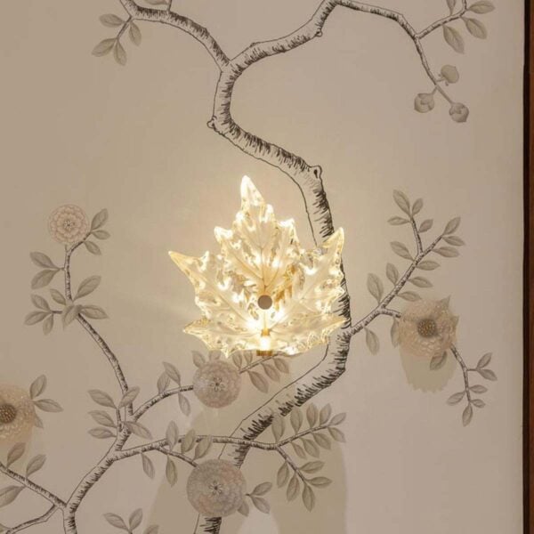 Elegant interior setting featuring the Lalique Champs-Élysées Wall Sconce in clear and frosted crystal, glowing softly to highlight its stylized oak leaf shape | Kneen & Co