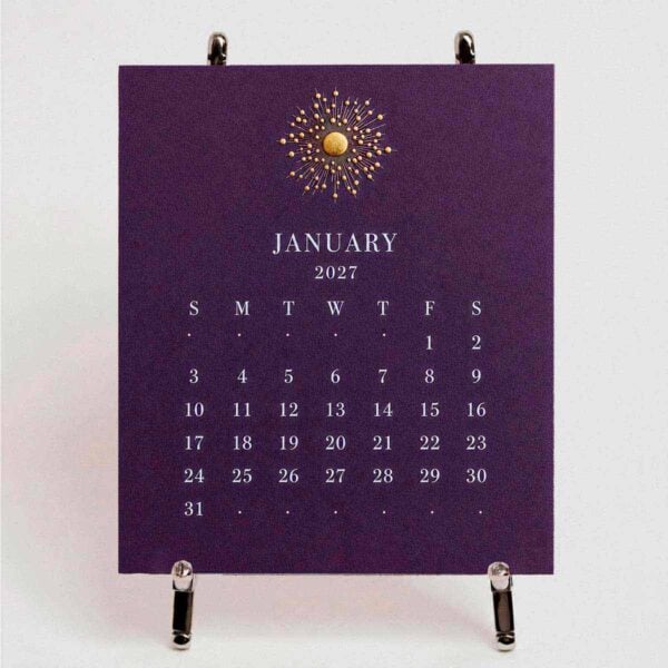 The Printery 2027 Calendar - Aubergine on the chrome easel, white text with starburst engraved in gold | Kneen & Co