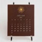 The Printery 2027 Calendar - Espresso, white text with starburst engraved in gold | Kneen & Co