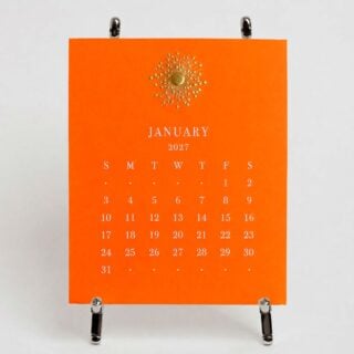The Printery 2027 Calendar - Orange, white text with starburst engraved in gold | Kneen & Co